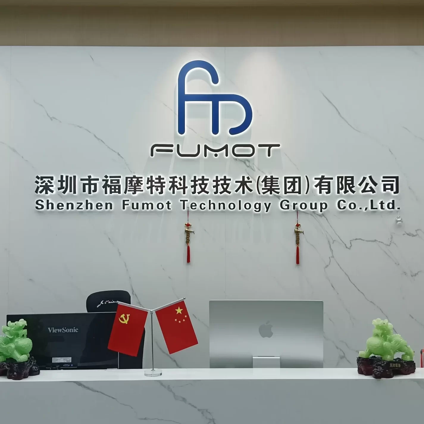 Reception desk of Shenzhen Fumot Technology Group Co., Ltd. with company logo, Chinese flags, and minimalist marble decor